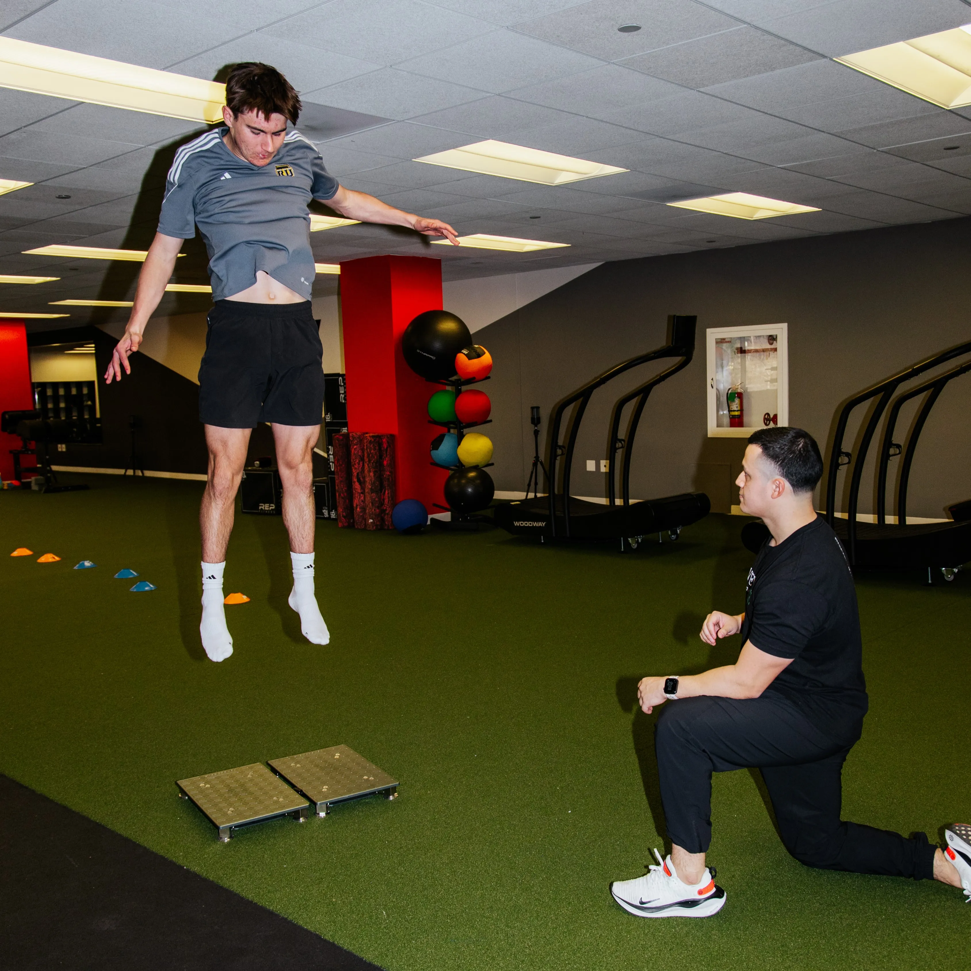 An athlete jumps on the VALD force plates while Dr. Benitez monitors him.
