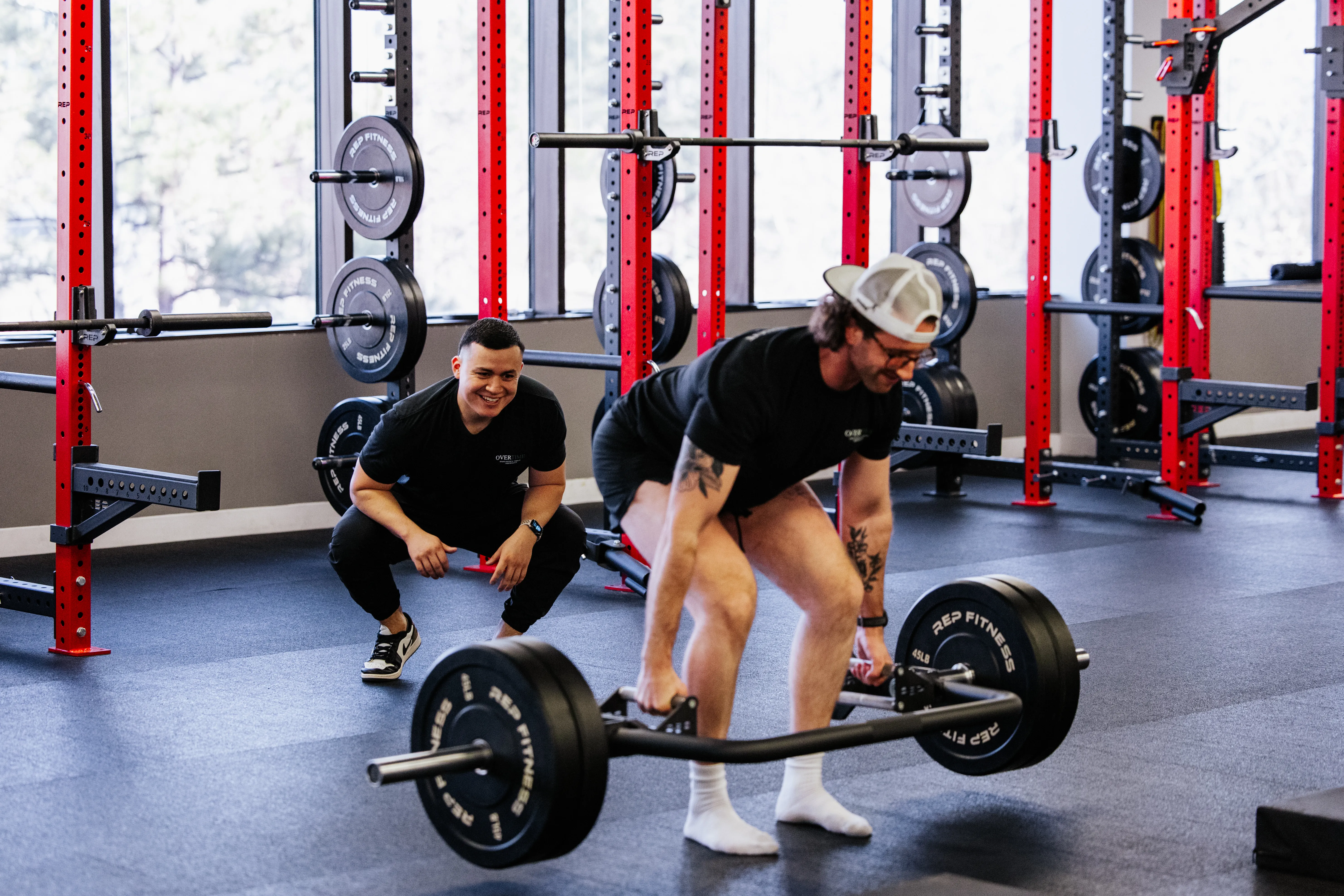 Dr. Benitez monitors a client performing weighted deadlifts in the OVERTIME gym.