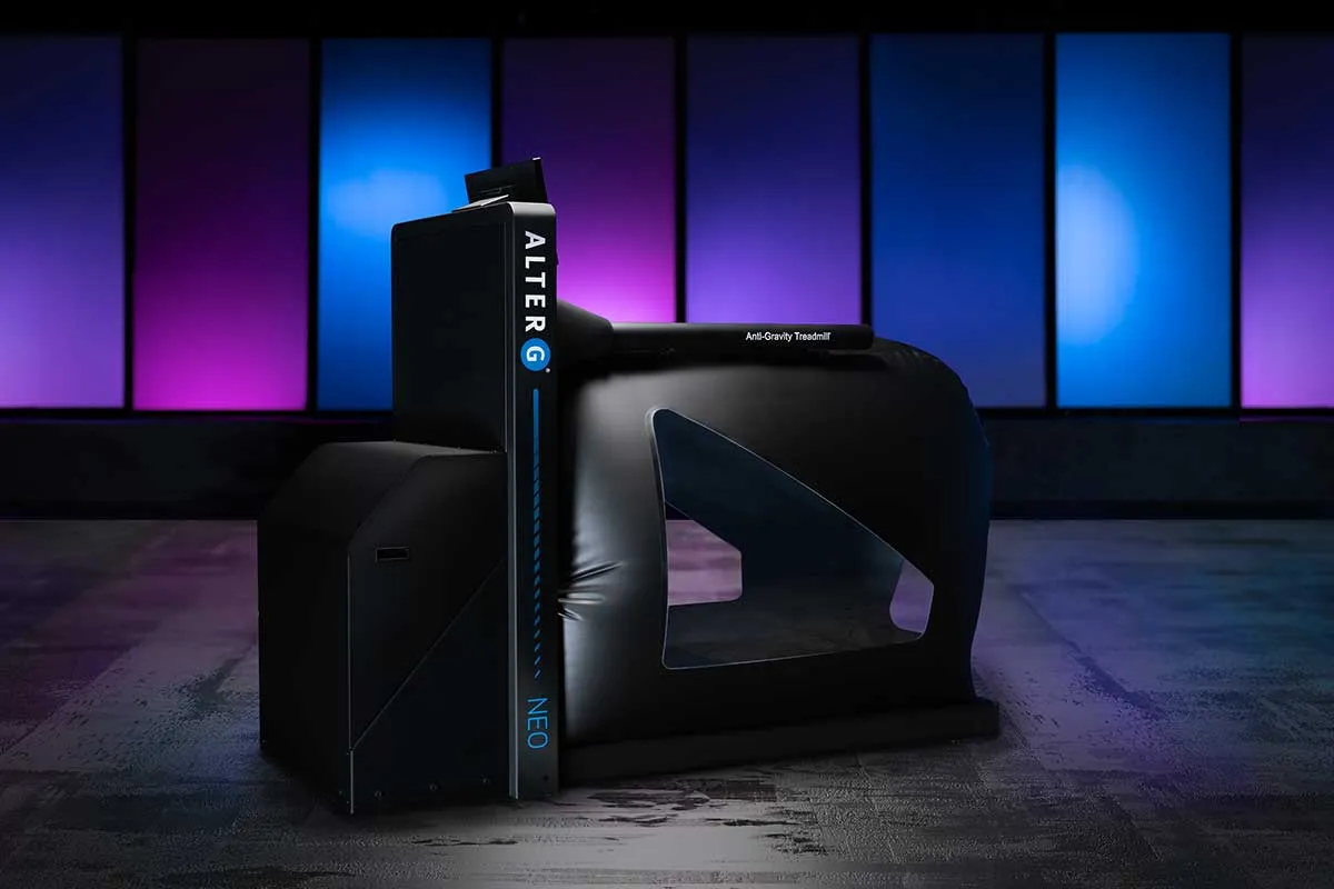 The AlterG ant-gravity treadmil infront of a multi-colored wall.