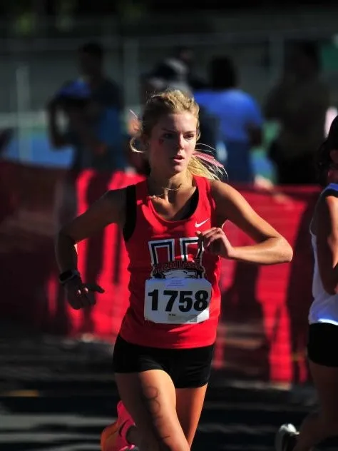 A runner competeing in a race for their school.